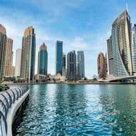Dubai Marina mit Blick auf blaues Wasser und moderne Wolkenkratzer unter strahlendem Himmel.