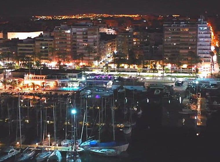 Vista nocturna del port de Torrevella amb vaixells i edificis prop del port.