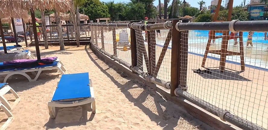 Àrea de sorra per a famílies amb tumbones i para-sols.