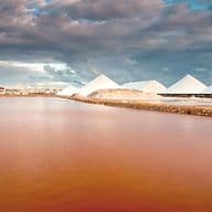 Vista panorámica de la laguna rosa con cinco dunas de sal y un cielo nublado