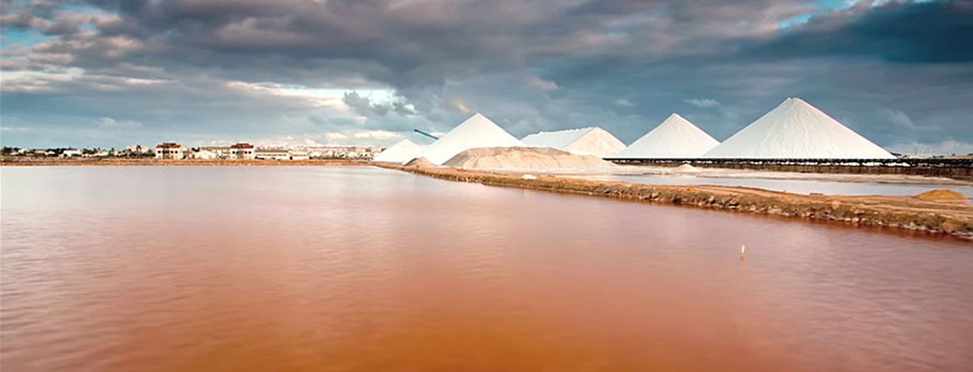 Vista panorámica de la laguna rosa con cinco dunas de sal y un cielo nublado