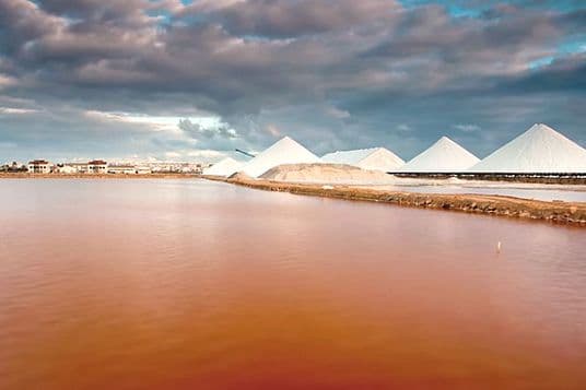Vista panorámica de la laguna rosa con cinco dunas de sal y un cielo nublado