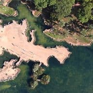 Panoramic view of a park in Torrevieja with trees, water and parches of land.