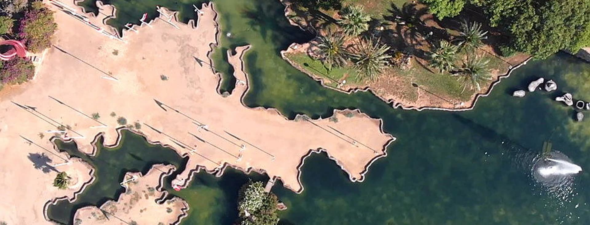 Vista panoràmica d'un parc a Torrevella amb arbres, aigua i parcel·les de terra.