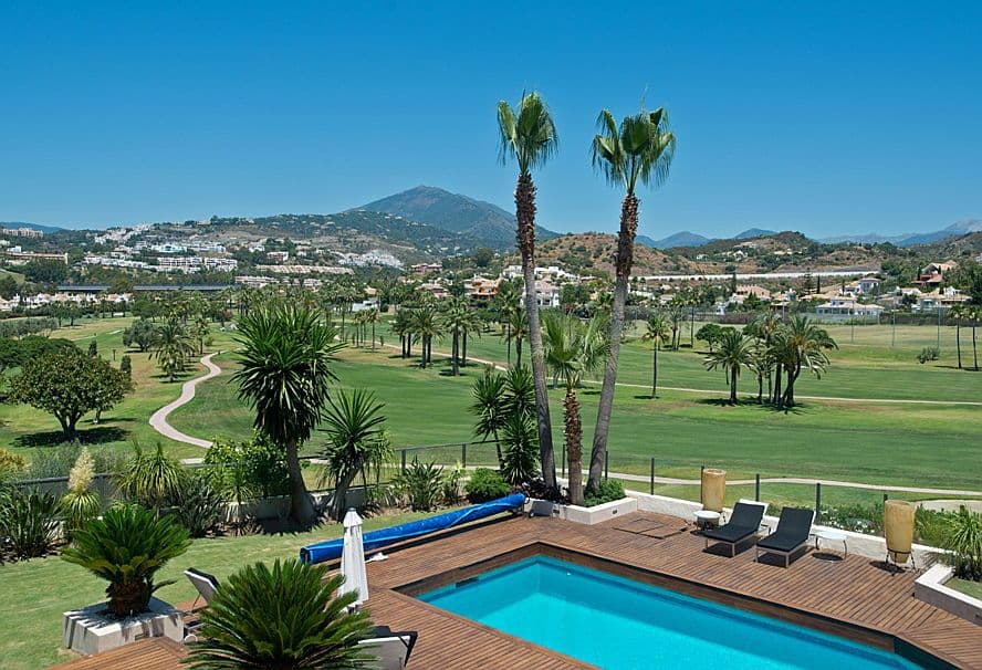 Green golf course with palm trees and La Concha mountain