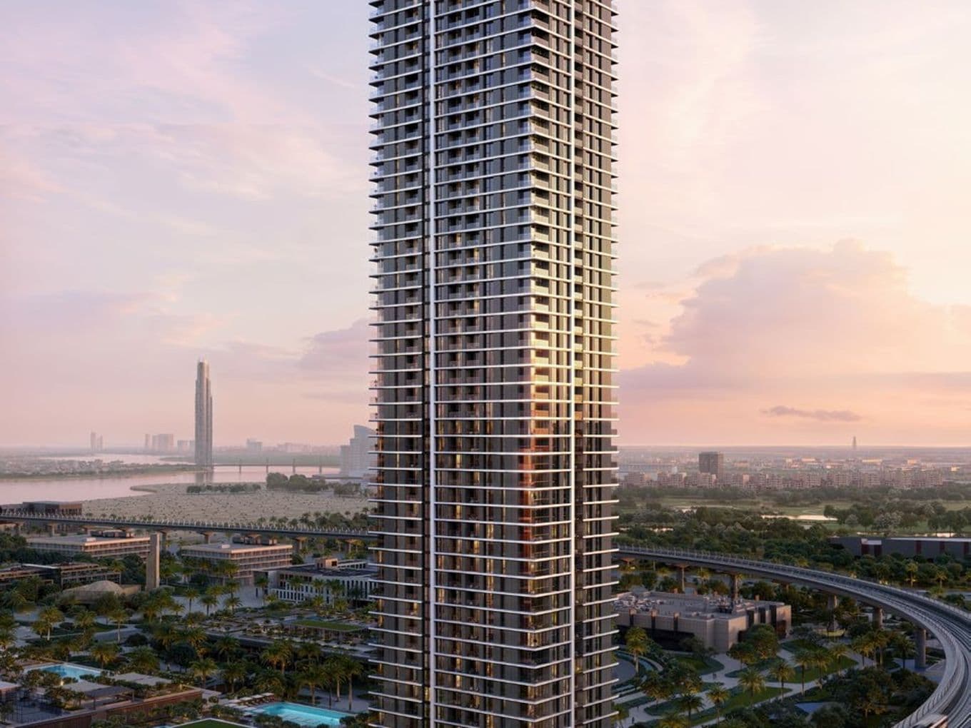 legant high-rise residential tower at sunset with landscaped podium gardens, swimming pools, and views over Dubai Creek.