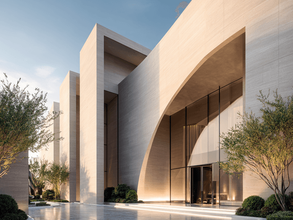 Modern building with large glass entrance, smooth stone walls, and minimalistic architecture. Surrounded by small trees under a clear sky.