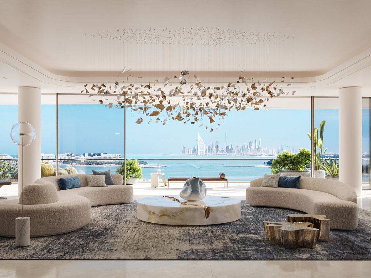 Luxuriöses Wohnzimmer mit geschwungenen Sofas, einem Marmortisch und einem Blick auf die Skyline der Stadt auf der anderen Seite des Wassers unter einem modernen Kronleuchter.
