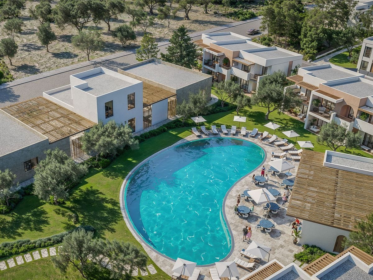 Aerial view of a resort featuring a kidney-shaped pool surrounded by sun loungers, lush greenery, and modern white buildings.