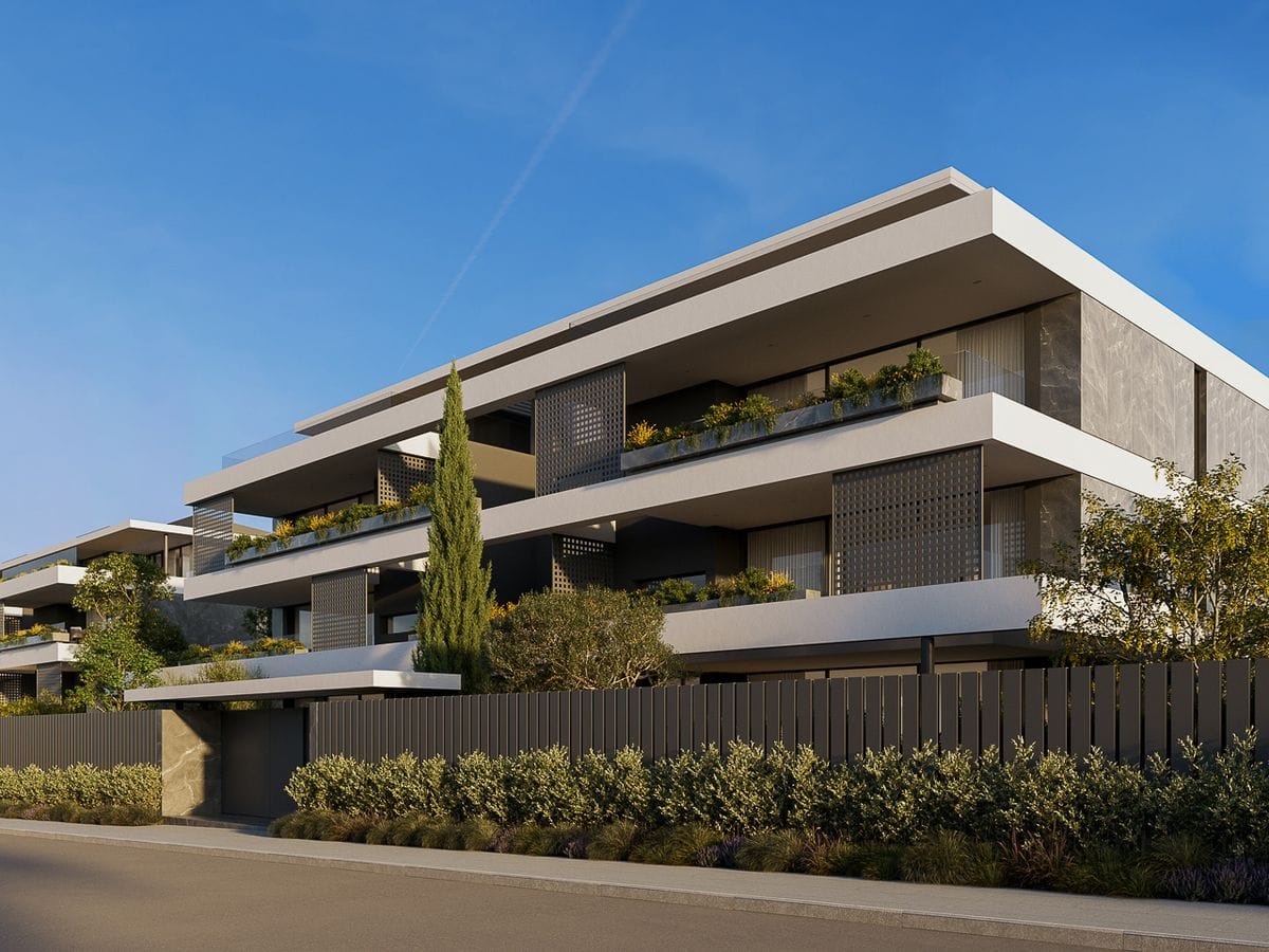 Modern three-story apartment building with wide terraces, planter boxes and greenery, minimalist white and gray facade under clear blue sky.