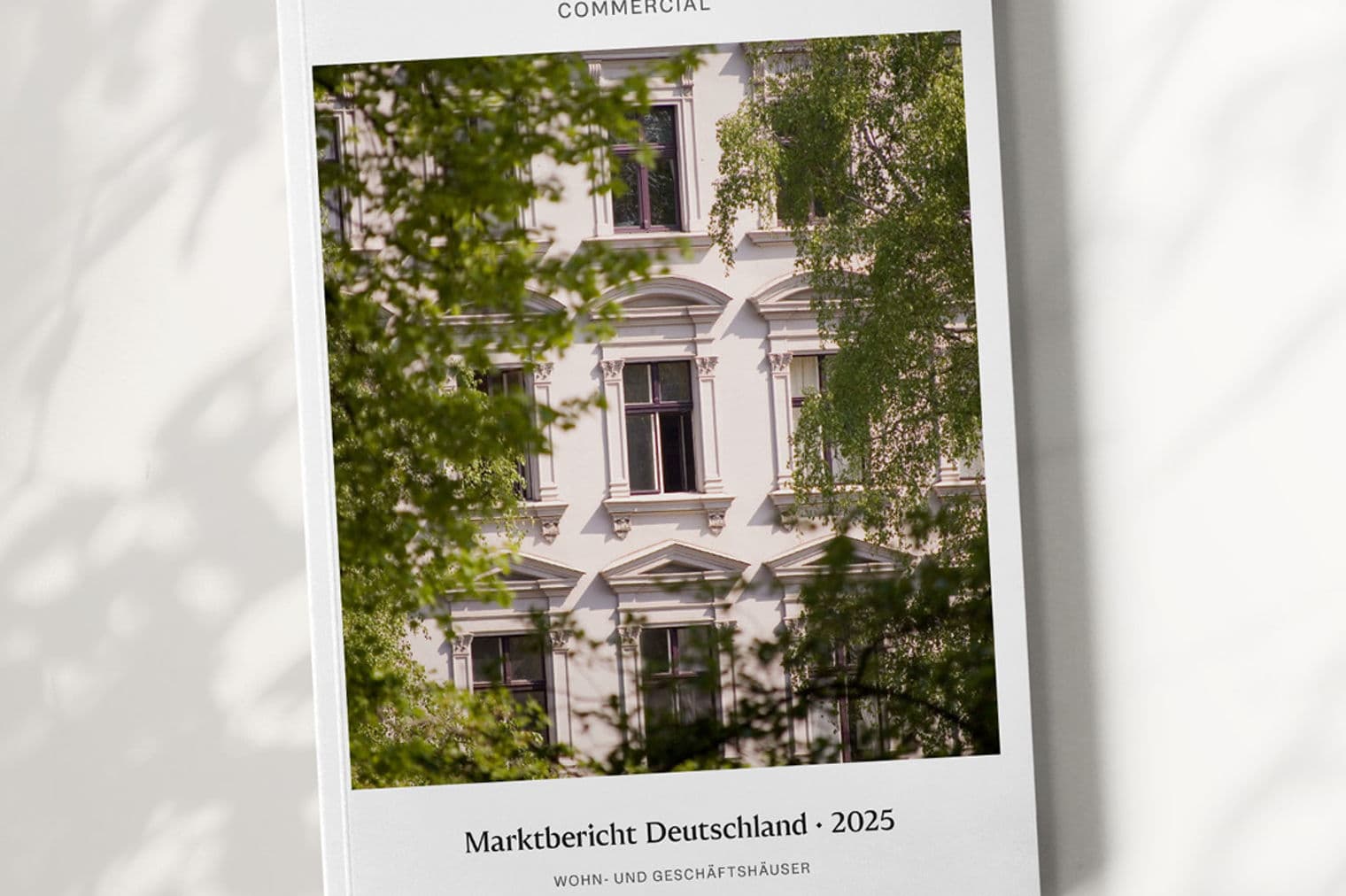 Engel & Völkers Commercial report cover. White building facade with dark windows framed by green trees. "Marktbericht Deutschland - 2025" text.