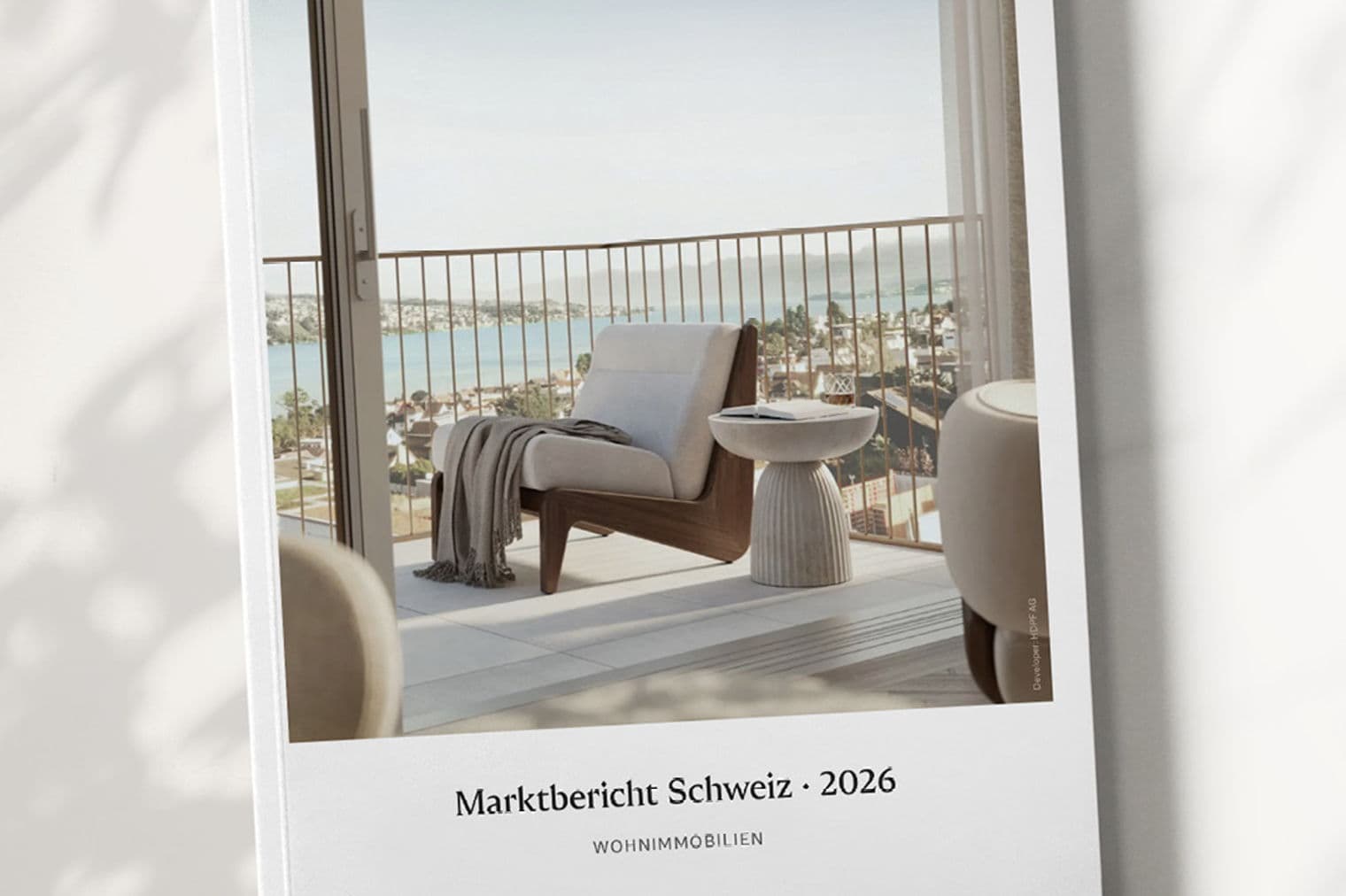 Engel & Völkers Broschüre "Marktbericht Schweiz 2026". Das Cover zeigt einen Balkon mit einem Stuhl mit Blick auf einen See.