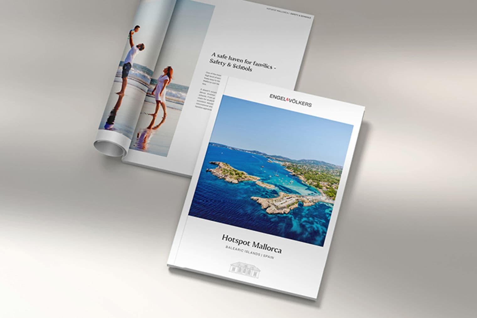 Engel & Völkers Immobilienbroschüren. Eine zeigt eine Familie an einem Strand, die andere eine Küstenansicht von Mallorca.