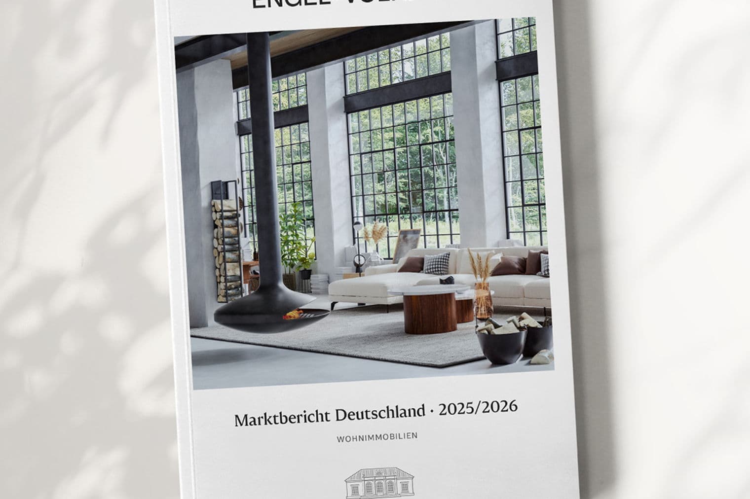 Engel & Völkers market report cover. Modern living room with black fireplace, white sofa, and large windows. Text: "Marktbericht Deutschland 2025/2026."