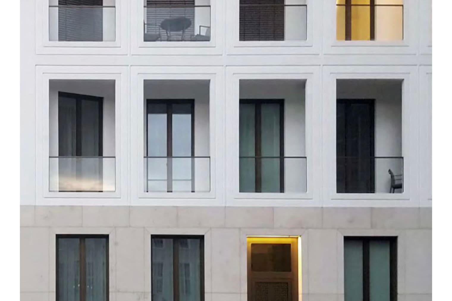 Facade of a white building with windows and balconies, some with blinds, and the Engel & Völkers logo at the top.
