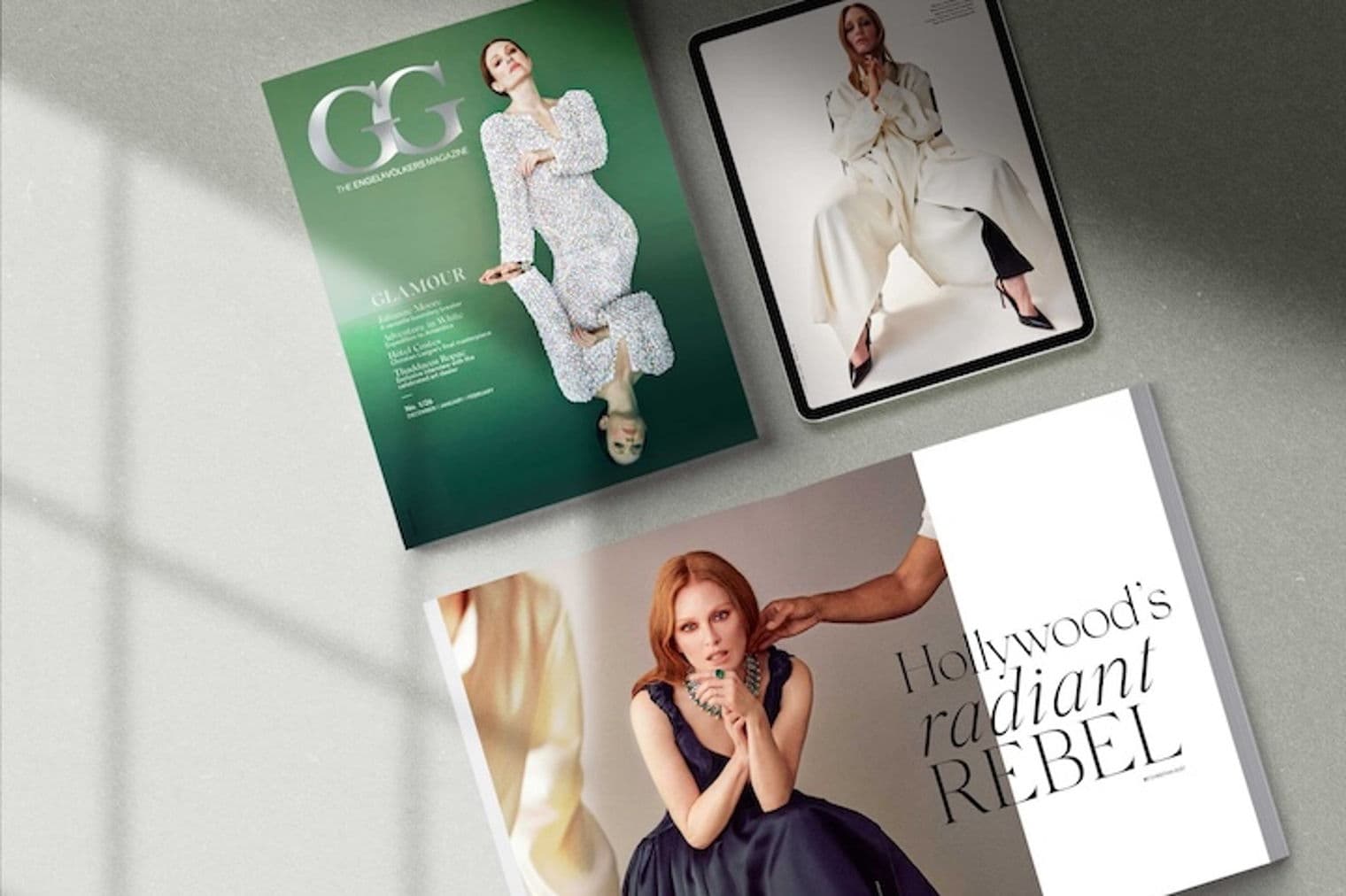 Drei Engel & Völkers Magazine und ein Tablet auf einer grauen Oberfläche. Die Magazine zeigen Frauen in modischer Kleidung. Ein Magazin ist grün, eines ist weiß, und das Tablet zeigt eine Frau in Weiß.