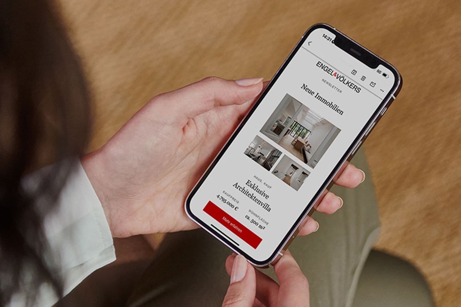 Eine Person hält ein Smartphone, auf dem ein Engel & Völkers Immobilien-Newsletter mit Villenangeboten angezeigt wird.