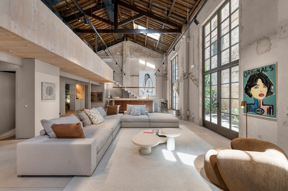 Spacious commercial loft interior in Mallorca with exposed wooden beams, large windows, and modern lounge areas