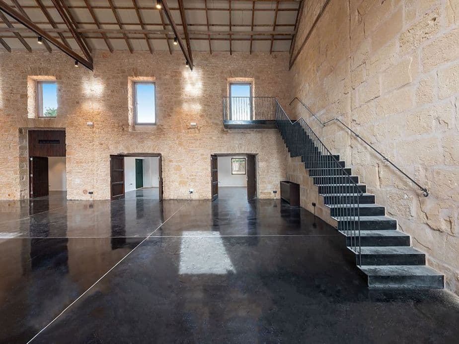 Open industrial space in Mallorca with warehouse interior, stone walls, and modern steel staircase