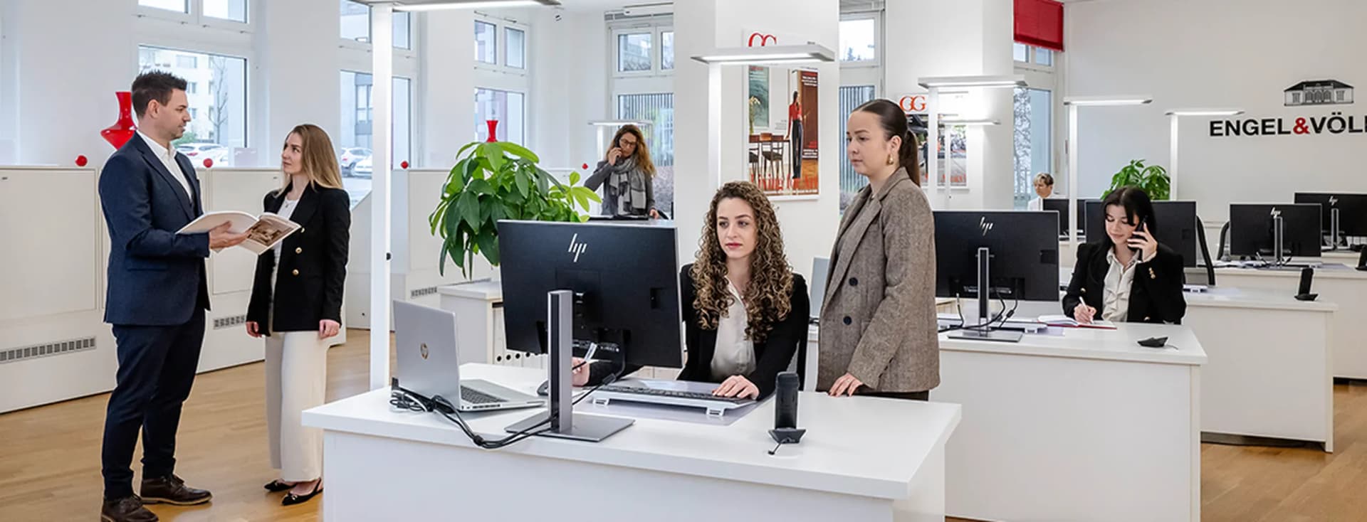 Real estate agents in the Engel & Völkers Bülach office assisting clients at the reception desk