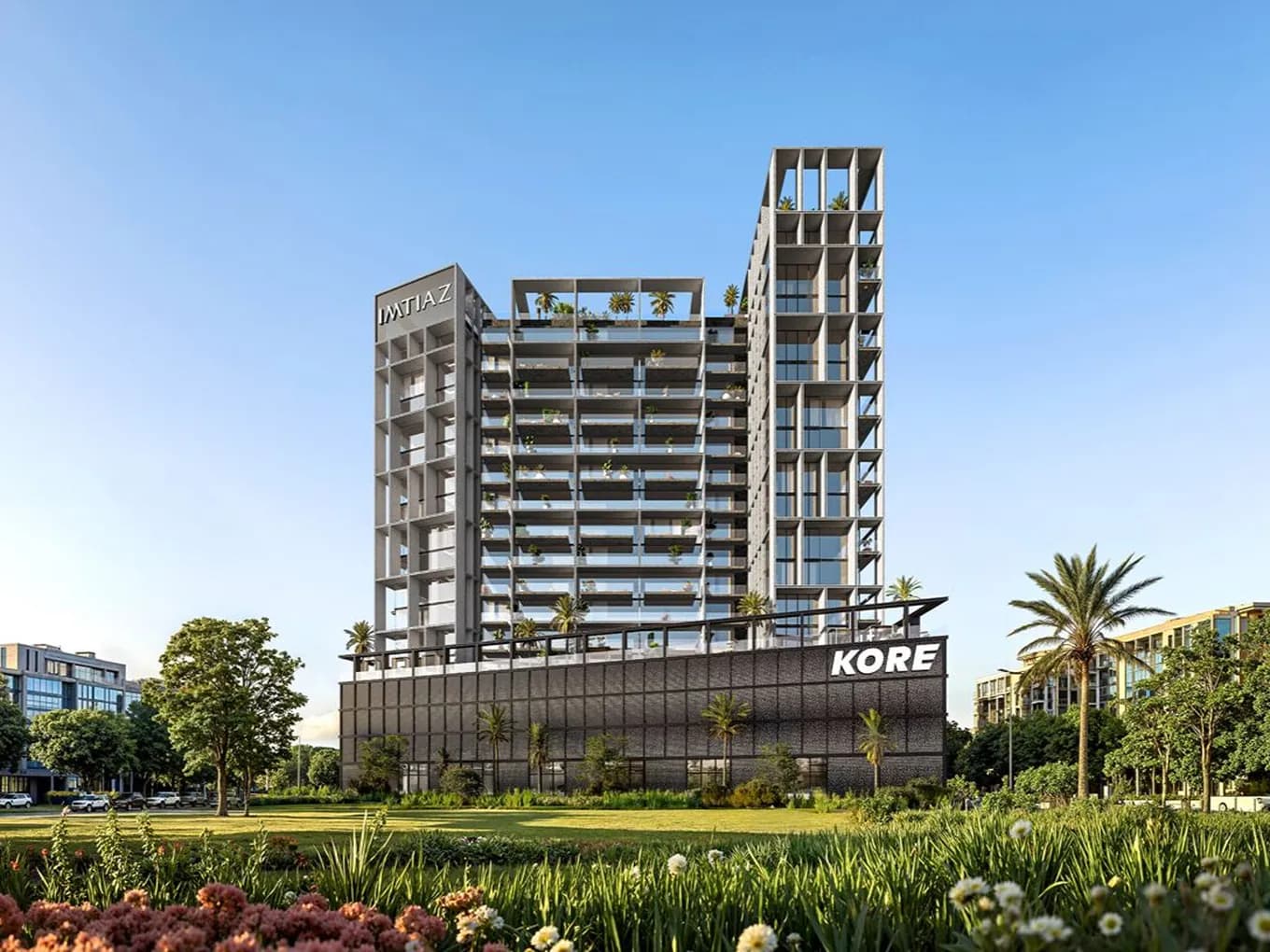 Modern high-rise with grid-like balconies and rooftop terraces; KORE sign on the lower facade, IMTIAZ tower on the side, landscaped foreground.