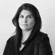 lack and white portrait of a woman with dark shoulder-length hair looking directly at the camera against a minimalist studio background.