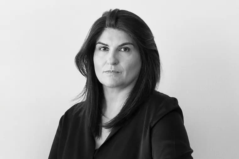 lack and white portrait of a woman with dark shoulder-length hair looking directly at the camera against a minimalist studio background.