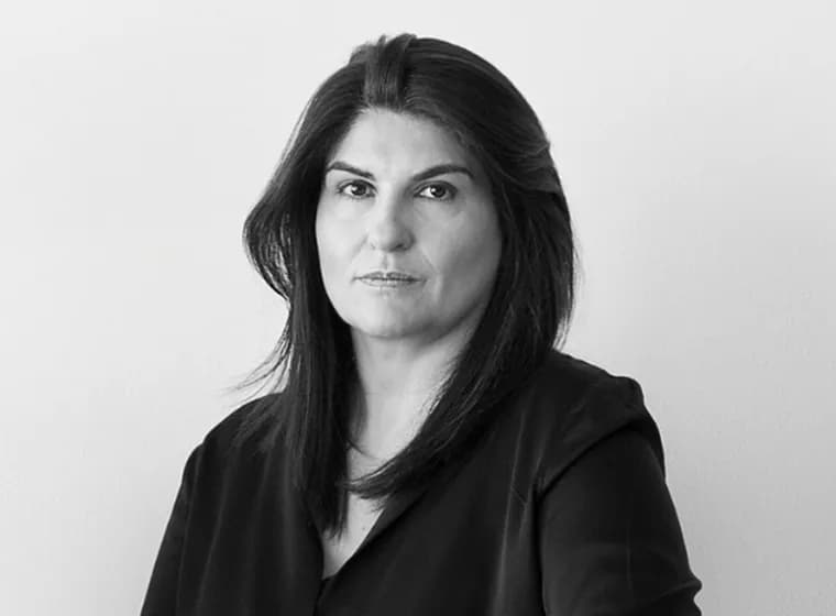 lack and white portrait of a woman with dark shoulder-length hair looking directly at the camera against a minimalist studio background.