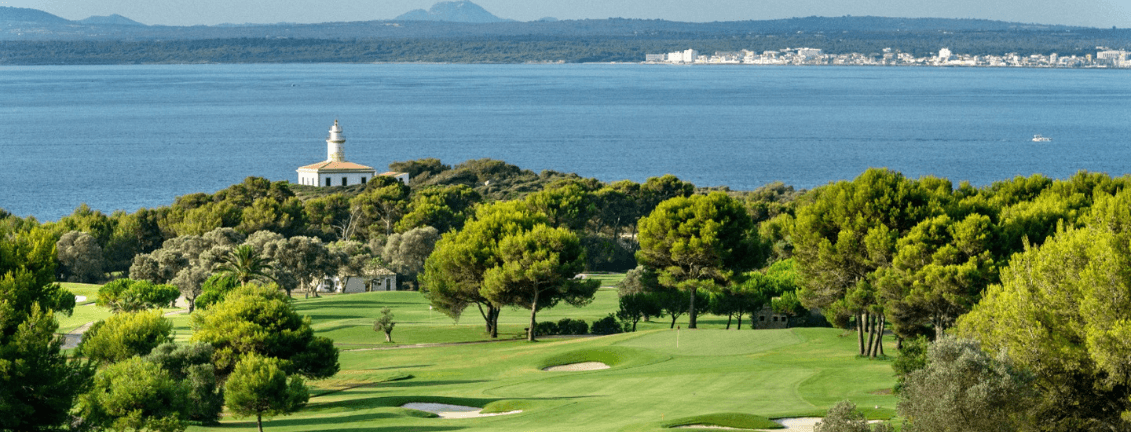 Vistes espectaculars al camp de golf amb els seus arbres i al mar, amb un far al fons.