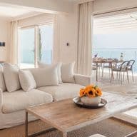 Bright open-plan living room with elegant contemporary furnishings, floor-to-ceiling sliding doors, and panoramic sea views