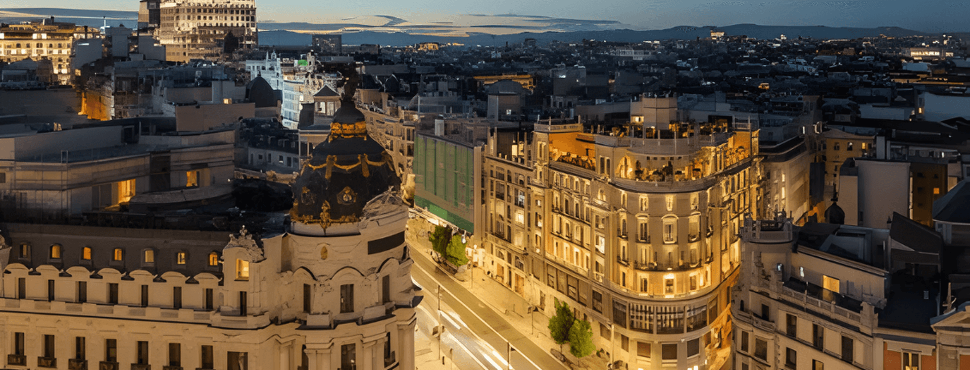 Luftaufnahme von Madrid bei Nacht, mit beleuchteten Gebäuden und verschwommenen Lichtern, die durch den fließenden Verkehr auf den Straßen verursacht werden.