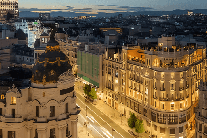 Vista aérea de Madrid de noche, con edificios iluminados y luces borrosas provocadas por el tráfico en movimiento en las calles.