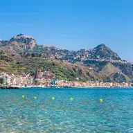 Scenic coastal town with clear turquoise waters and mountains rising in the background