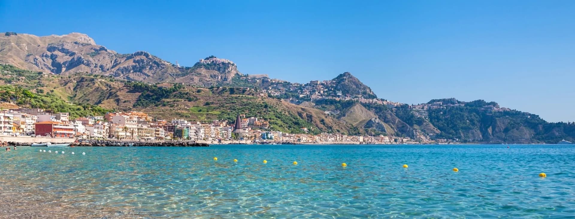 Scenic coastal town with clear turquoise waters and mountains rising in the background