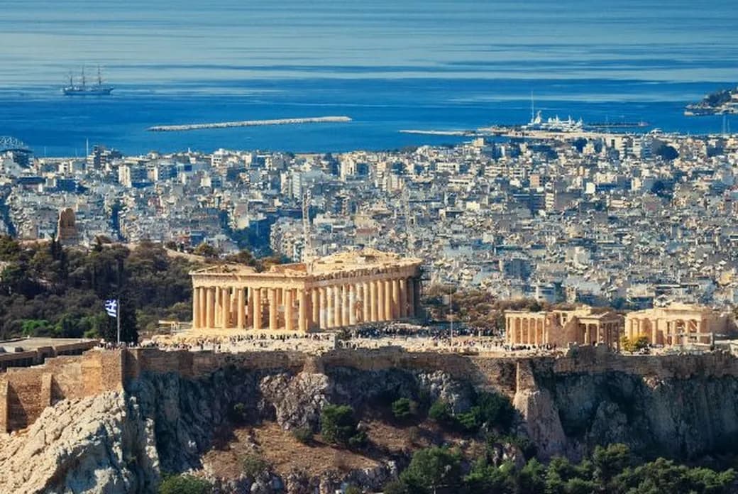 Panoramablick auf Athen mit der Akropolis, dem Parthenon und der Küstenlinie der Stadt, die sich bis zur Ägäis erstreckt.