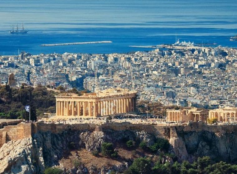 Panoramic view of Athens featuring the Acropolis, the Parthenon, and the city's coastline stretching to the Aegean Sea.