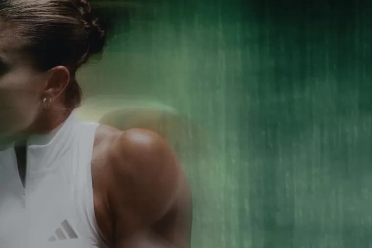 Intense side-profile shot of tennis player Maria Sakkari focused during movement against a dark textured background.