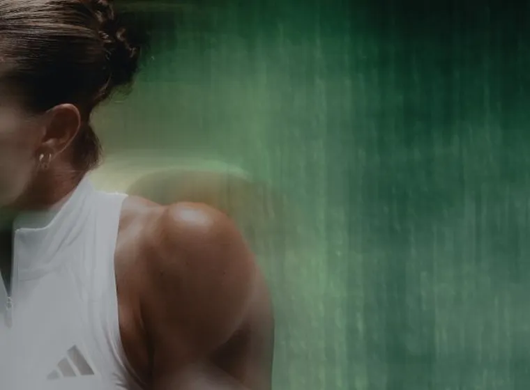 Intense side-profile shot of tennis player Maria Sakkari focused during movement against a dark textured background.