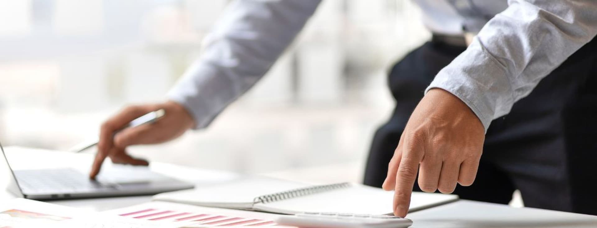 Business professional reviewing financial reports and working on a laptop in a modern office environment