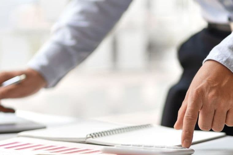 Business professional reviewing financial reports and working on a laptop in a modern office environment