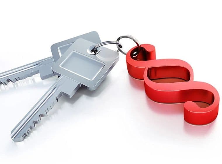 Three silver keys on a keyring with a red paragraph/section (§) symbol keychain on a white background.
