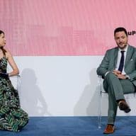 Panel discussion at White Paper The Event featuring a moderator and guest speaker on stage during a live business conversation
