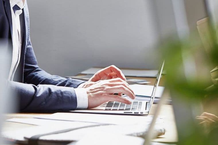 Business professional working on a laptop in a modern office environment with natural light and contemporary workspace design