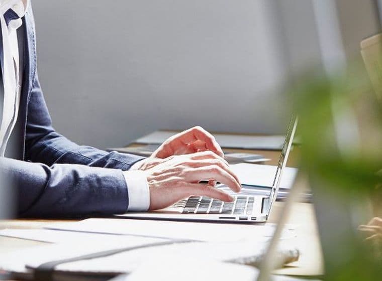 Business professional working on a laptop in a modern office environment with natural light and contemporary workspace design