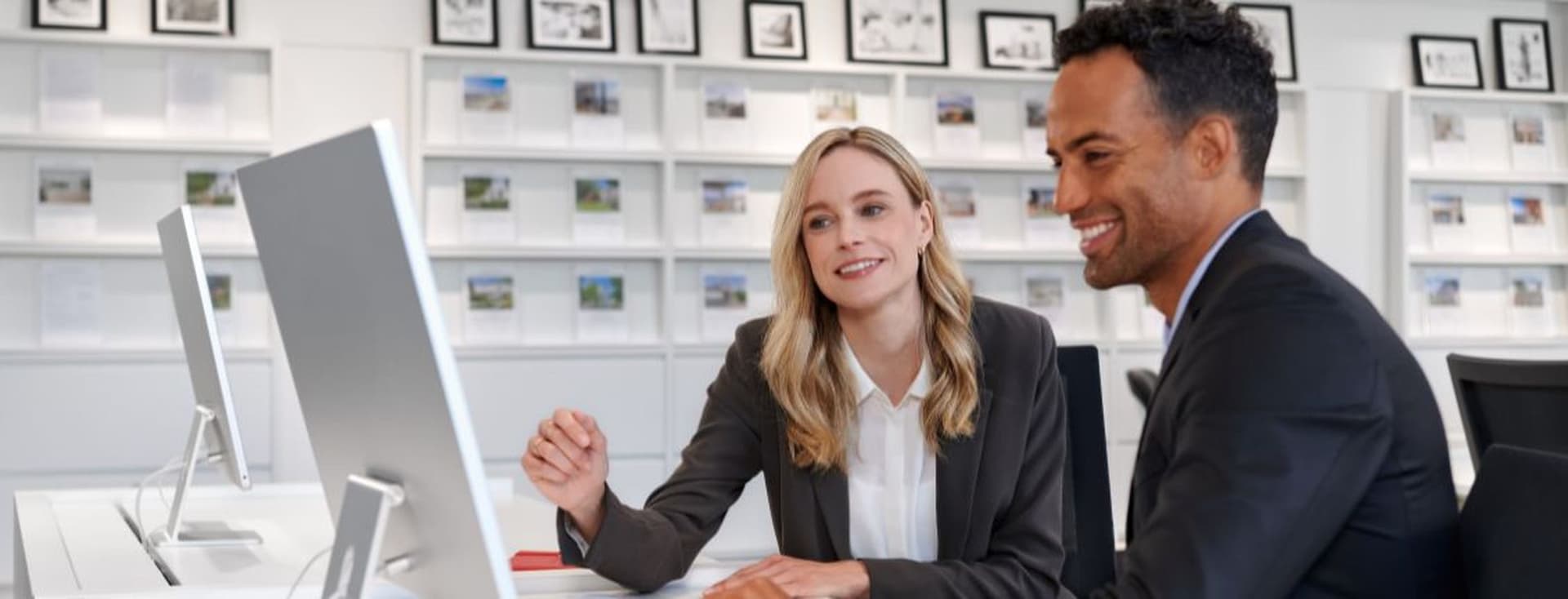 A man and a woman in business attire looking at a computer screen in an office
