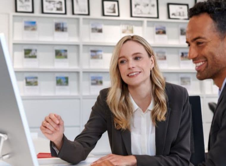A man and a woman in business attire looking at a computer screen in an office