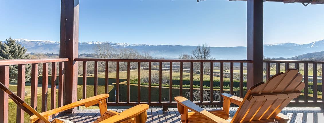 Balcony with two chairs in the sun and views of the mountains.