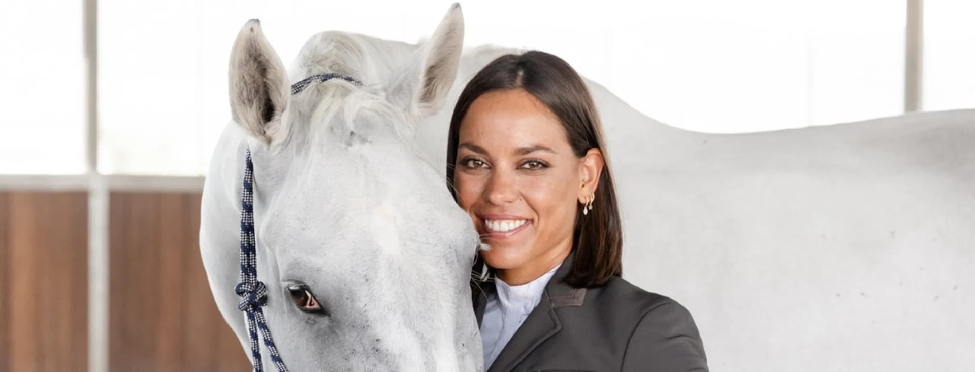 Portrait of a female equestrian wearing a riding helmet and vest, looking attentively into the distance.