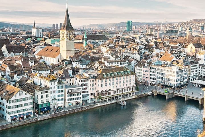 Aerial view of Zurich's historic city center showing luxury waterfront properties along the Limmat River, featuring traditional Swiss architecture, church spires, and high-value real estate in Switzerland's most expensive property market