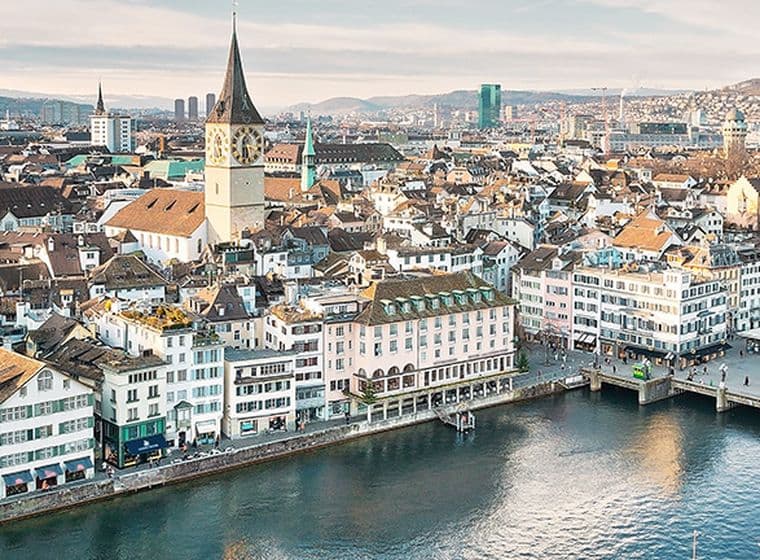 Aerial view of Zurich's historic city center showing luxury waterfront properties along the Limmat River, featuring traditional Swiss architecture, church spires, and high-value real estate in Switzerland's most expensive property market